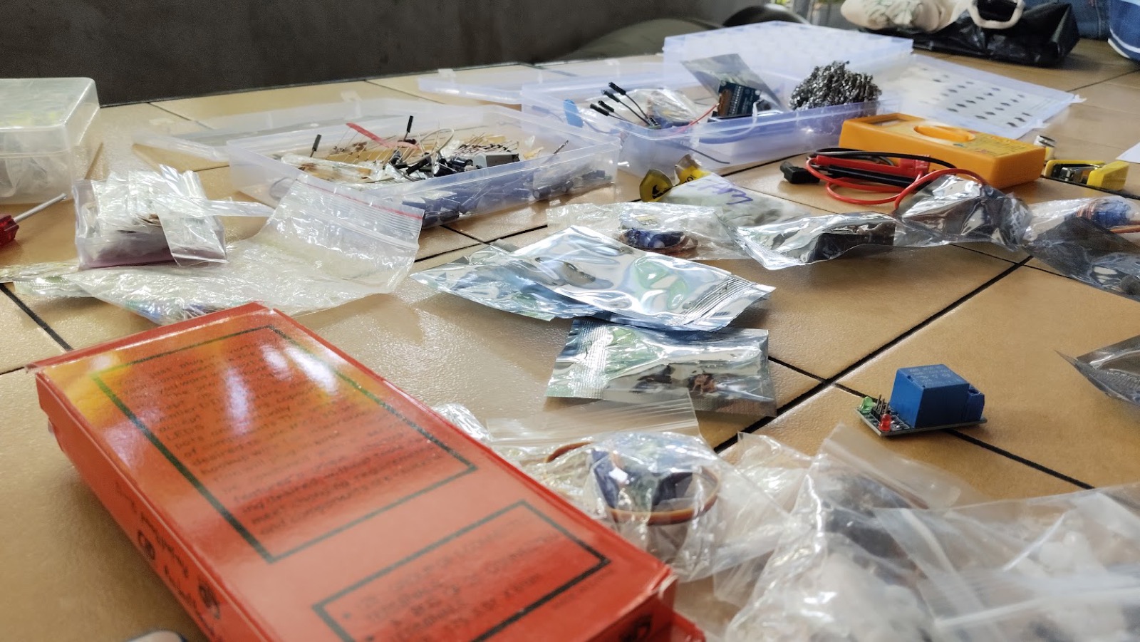 Table of components — breadboards, sensors, relays and a multimeter — laid out for the hardware jam